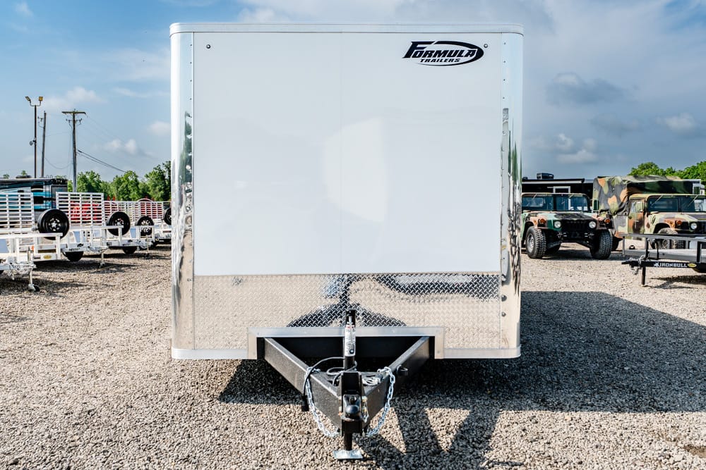 Front view of a white enclosed cargo trailer with a diamond-plate lower panel and a hitch on a gravel lot.