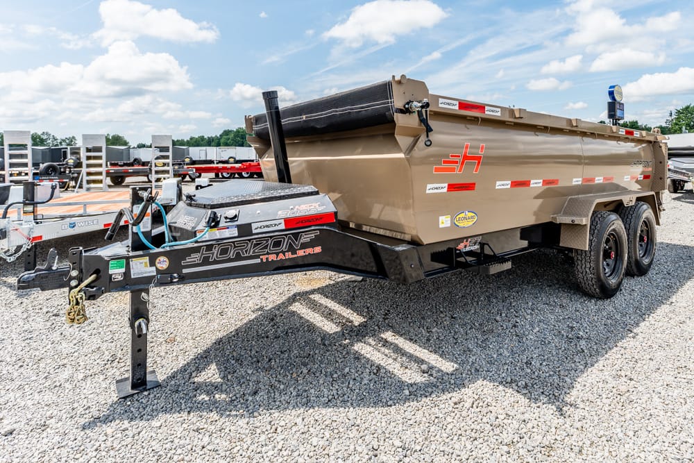Tan Horizon dump trailer on a gravel lot, attached to a hitch, with dual axles and protective frame rails.