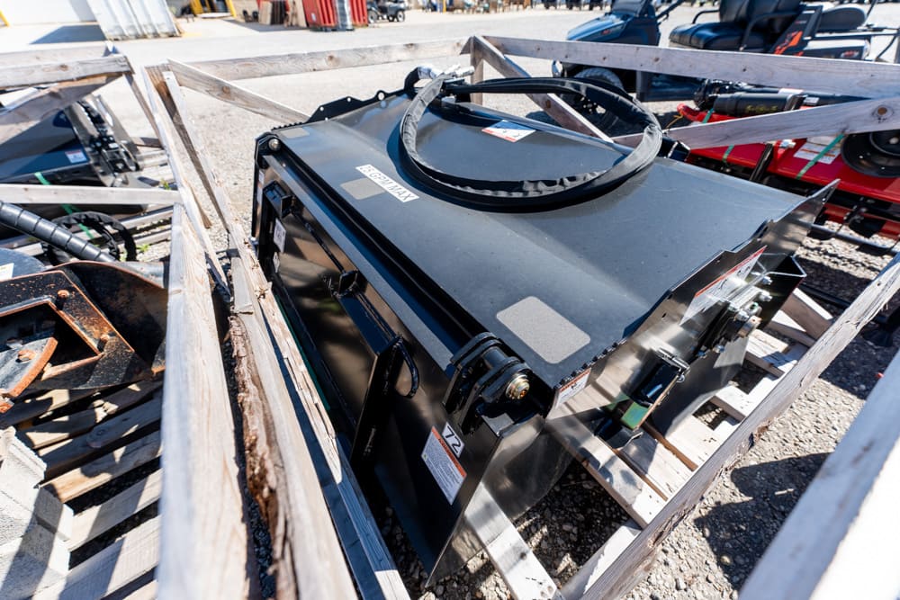 Black industrial machine in a wooden crate outdoors, with a coiled cable on top.