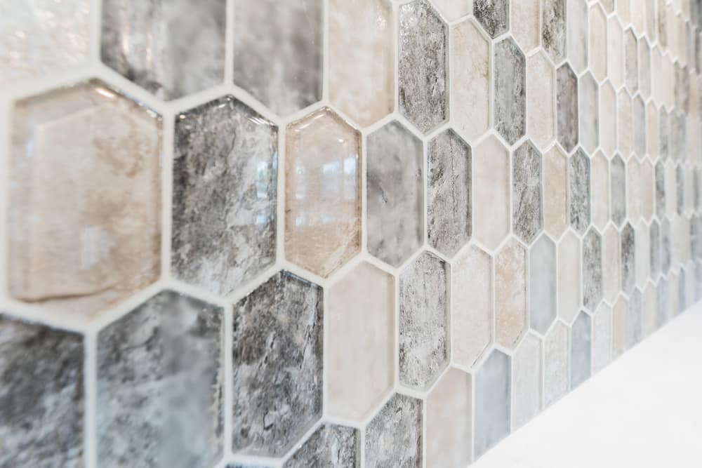 Hexagonal tile wall in beige, gray, and cream tones forming a neutral mosaic in a hallway or room edge detail.