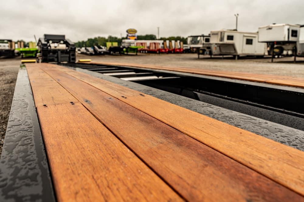 Wet wooden planks on a flatbed trailer with a trailer yard in the background.