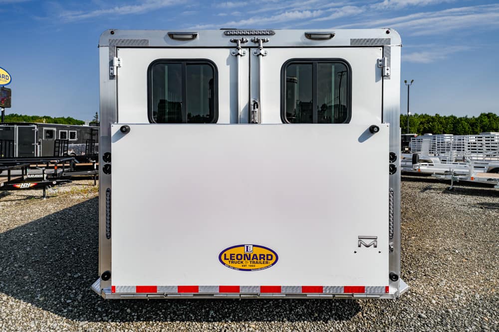 Rear view of a white trailer with two small windows, vertical latch bars, and a Leonard logo on the back.