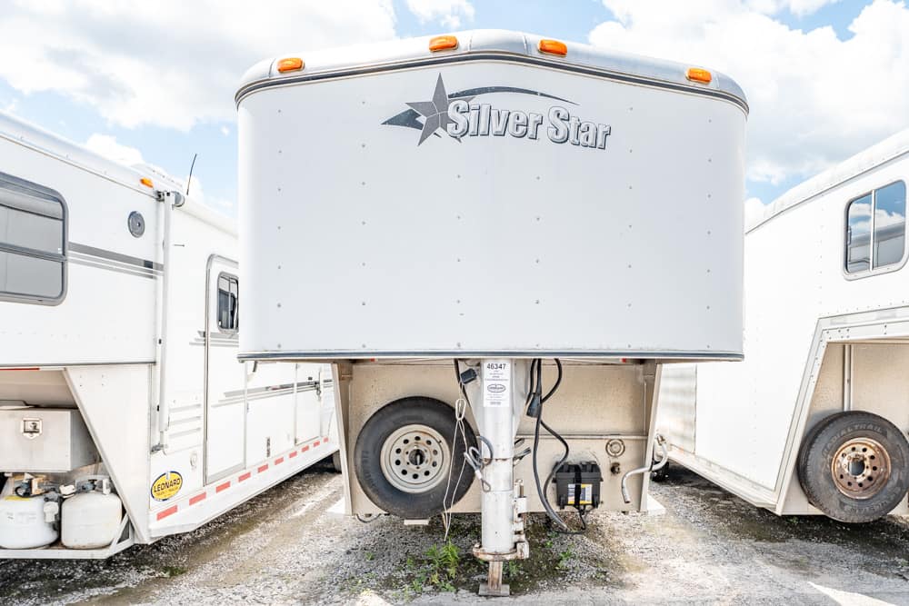 White travel trailer with a prominent 'Silver Star' logo, parked between two other large trailers on a gravel lot.