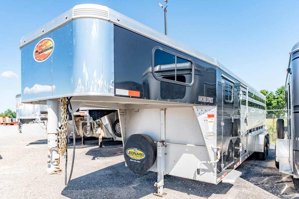 Gooseneck trailer parked in a lot, black and gray with Ranch Express branding and a Leonard spare-tire cover in the foreground.