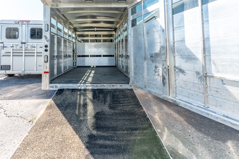 Interior of an aluminum horse trailer with the rear ramp lowered for loading.