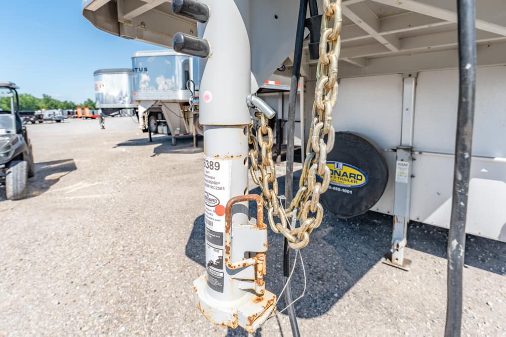 Close-up of a rusted trailer hitch with heavy chains hanging in a truck yard.