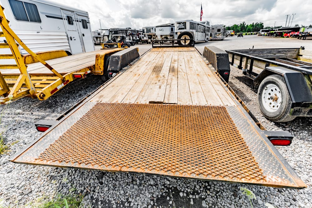 Rusty diamond-plate loading ramp on a flatbed trailer in a truck yard.
