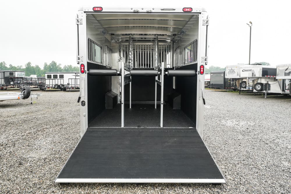 Open horse trailer with the back ramp lowered, showing partitioned stalls and divider rails inside.