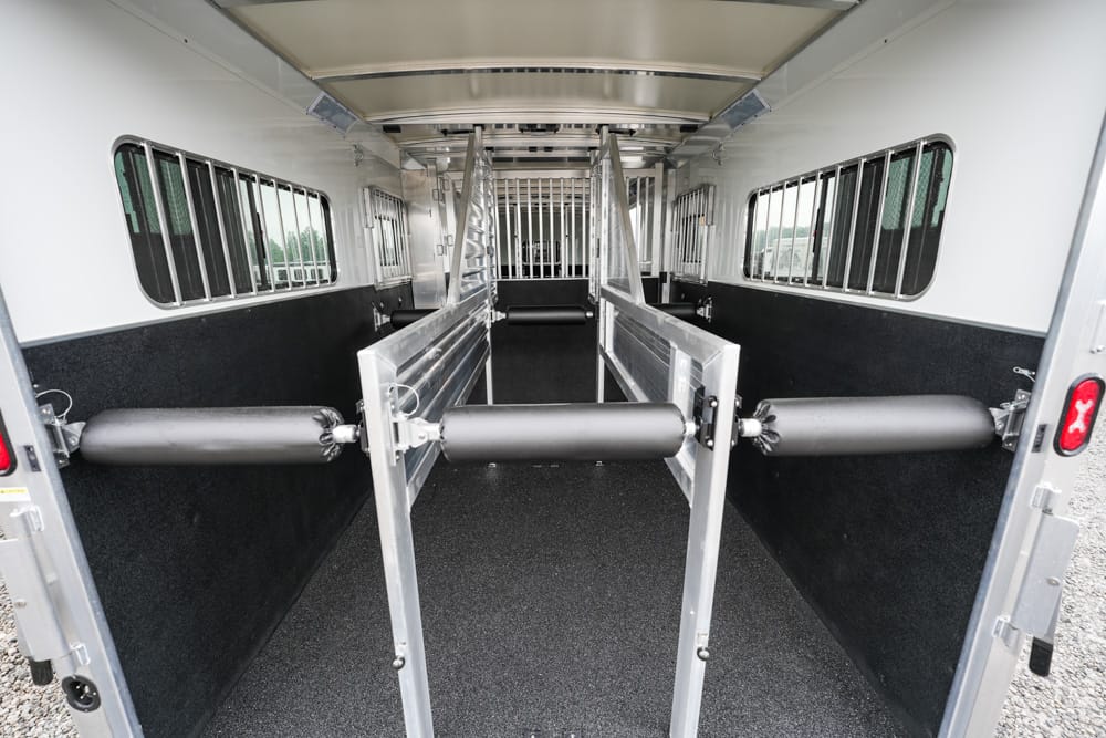 Interior of a horse trailer with partitioned stalls and padded dividers along the sides.