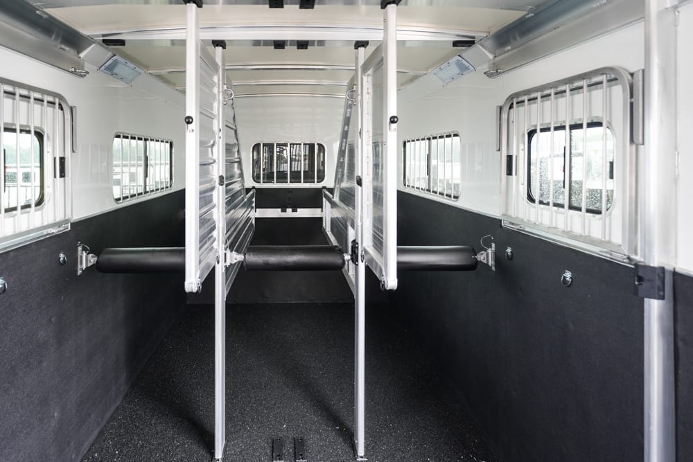 Interior of a horse trailer with divider stalls and padded breast bars, empty and ready for horses