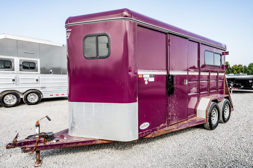 Purple horse trailer with diamond-plate front, parked on gravel, hitch in foreground.