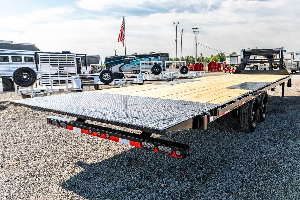 Flatbed trailer with wooden deck and diamond-plate ramp in a lot of trailers and RVs