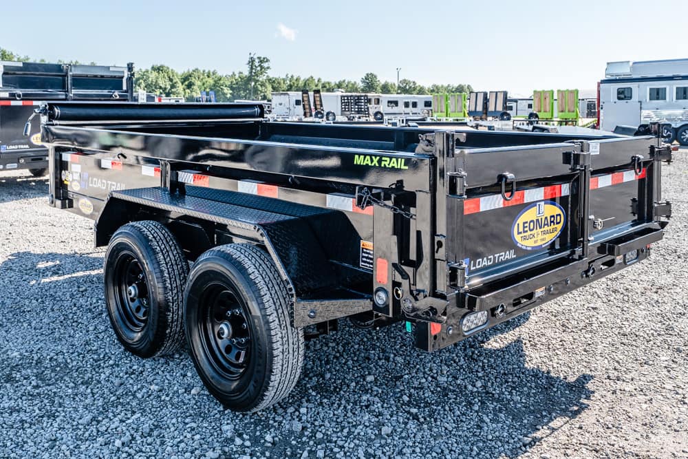 Black dual-axle dump trailer with Leonard logo parked on a gravel lot, side rails and reflectors visible in the scene.