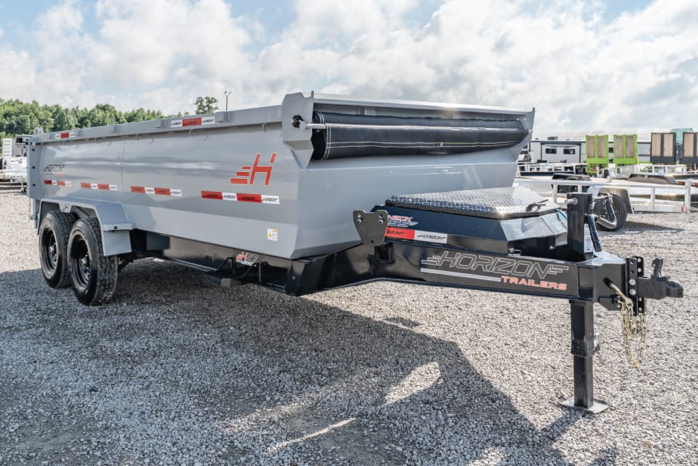 Gray Horizon trailer dump trailer with dual axles on a gravel lot, side view showing logo and hitch point at front.