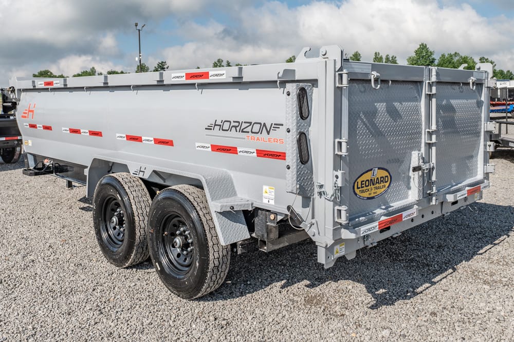 Dual-axle Horizon dump trailer parked on a gravel lot, silver with red reflective stripes and a Leonard Trailer logo on the rear gate.