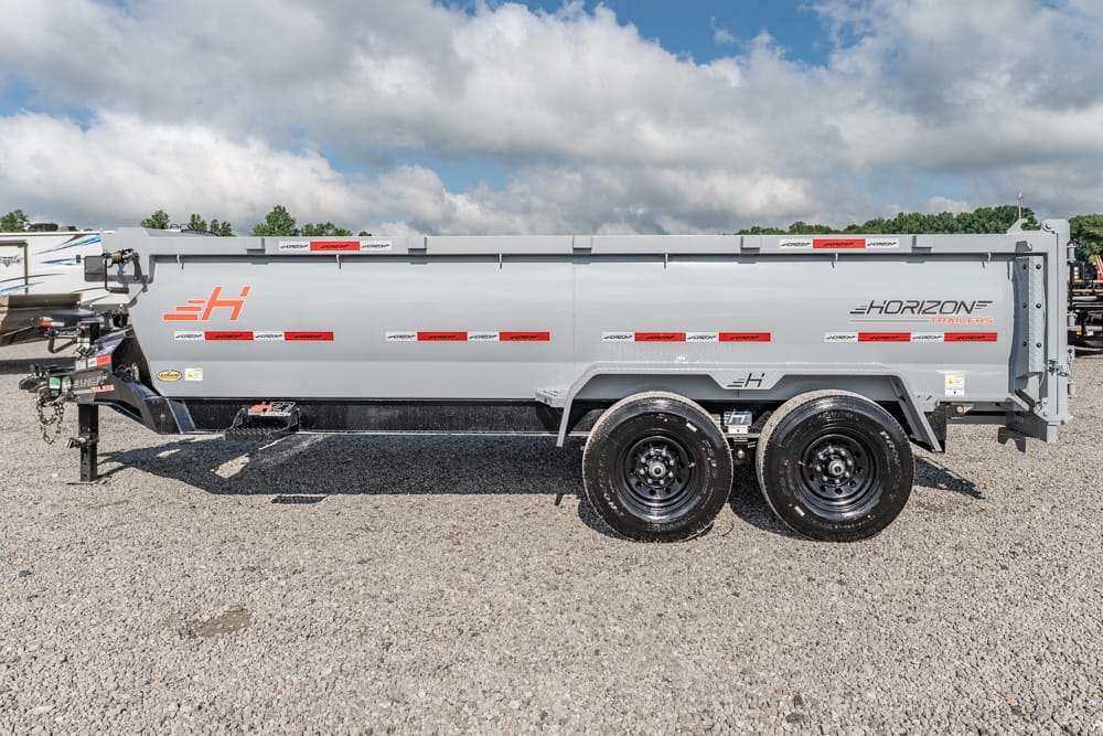 Gray Horizon dump trailer with dual axles on a gravel lot, showing red reflective strips and branding