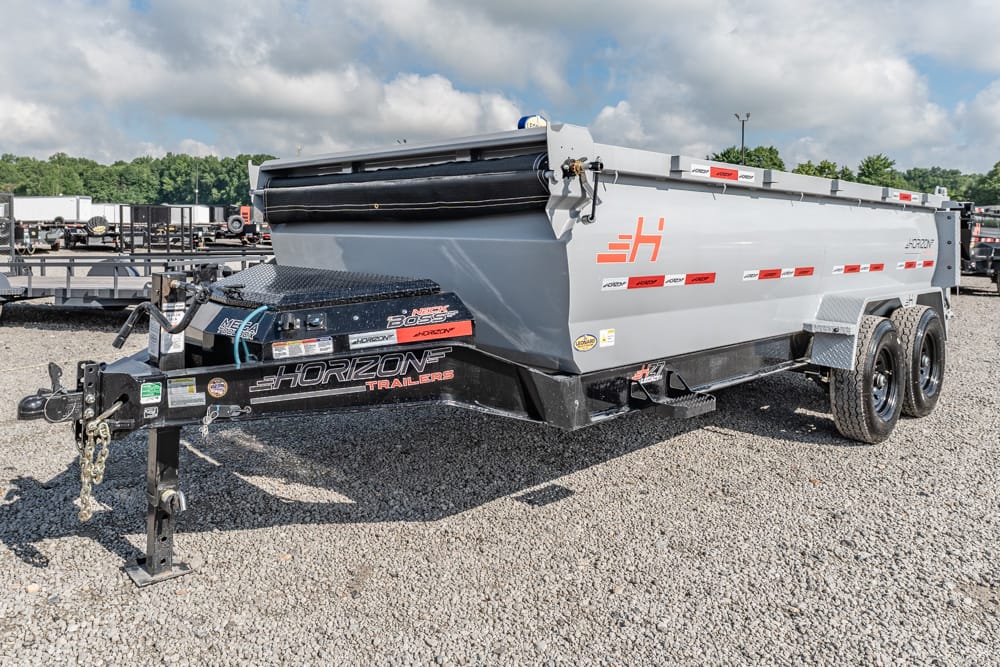 Grey Horizon dump trailer with dual wheels and chain hitch in a gravel lot; attached to a black front tongue by a hitch ball.
