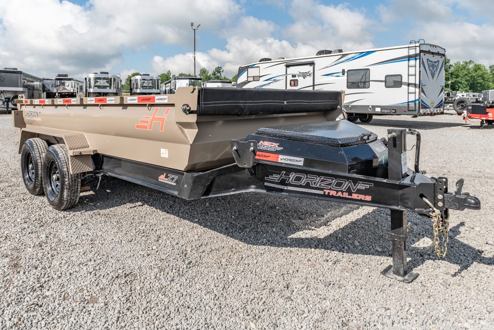 Tan Horizon dump trailer with dual rear axles on a gravel lot, connected to a black Horizon hitch, with RVs in the background.