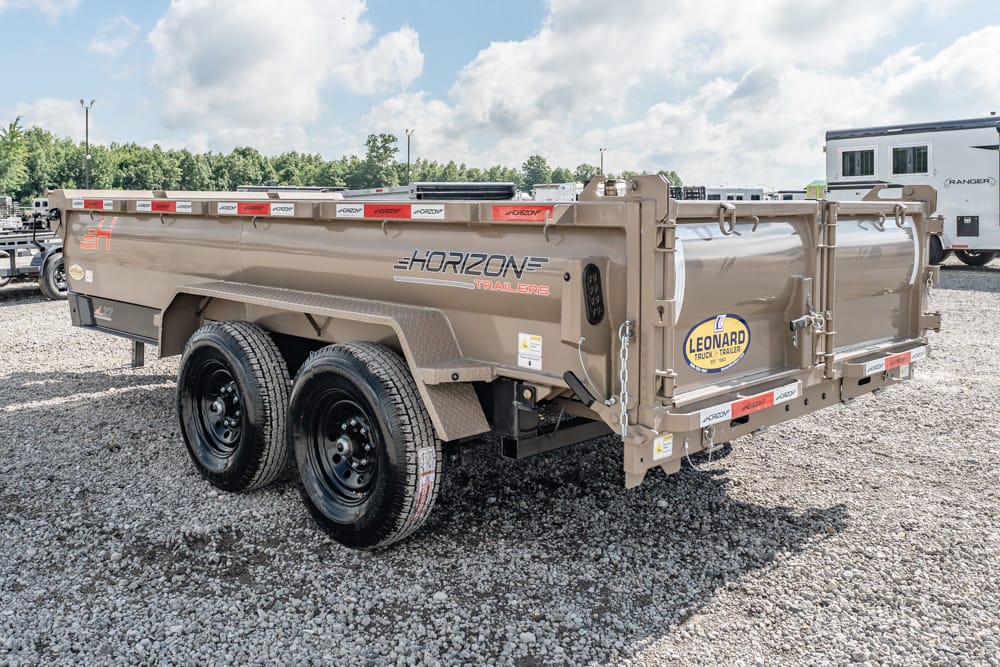 Tan Horizon dump trailer with dual axles on a gravel lot; Leonard Truck Trailer sticker on rear gate.