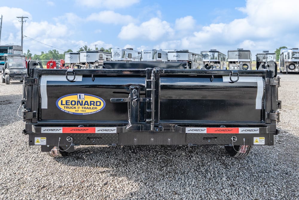 Rear view of a black Leonard truck trailer on a gravel lot, with a blue-and-yellow Leonard logo and horizon branding on the bumper, campers in the background
