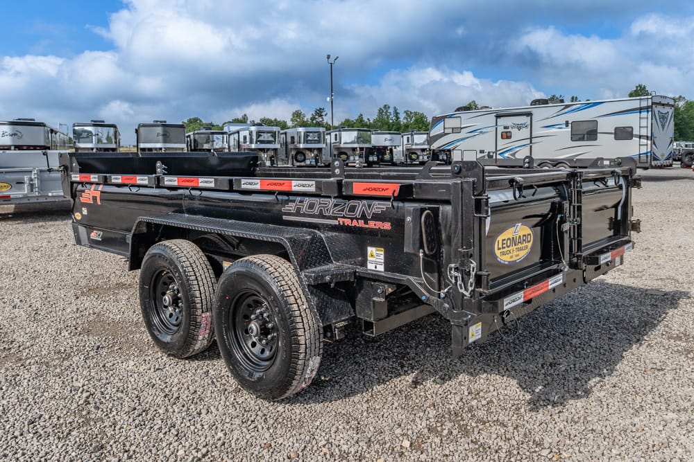 Black dual-axle utility trailer with stake sides in a gravel lot, Horizon Trailers branding and RVs in the background