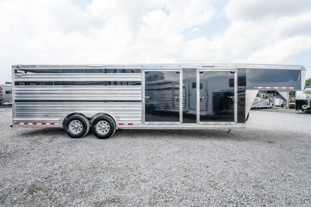 Silver two-axle enclosed horse trailer on a gravel lot with two doors and a front hitch, under a cloudy sky