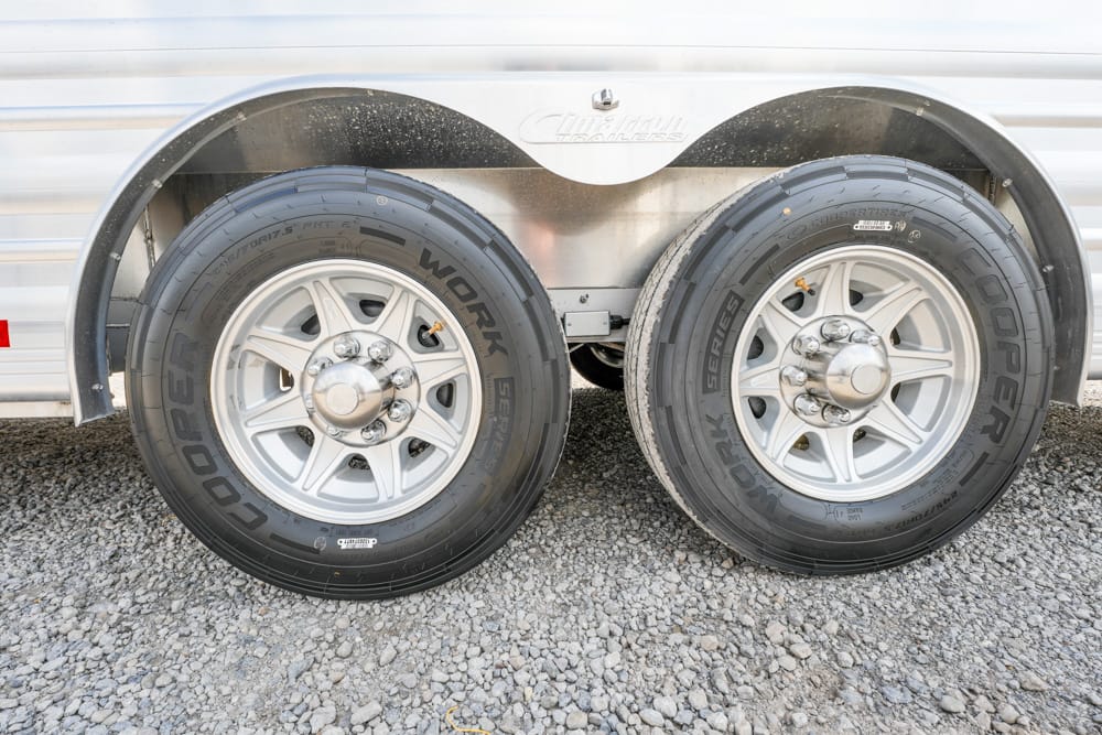 Dual‑axle trailer wheels with 2 Goodyear Work Series tires, silver rims, and metal fenders on a gravel surface?