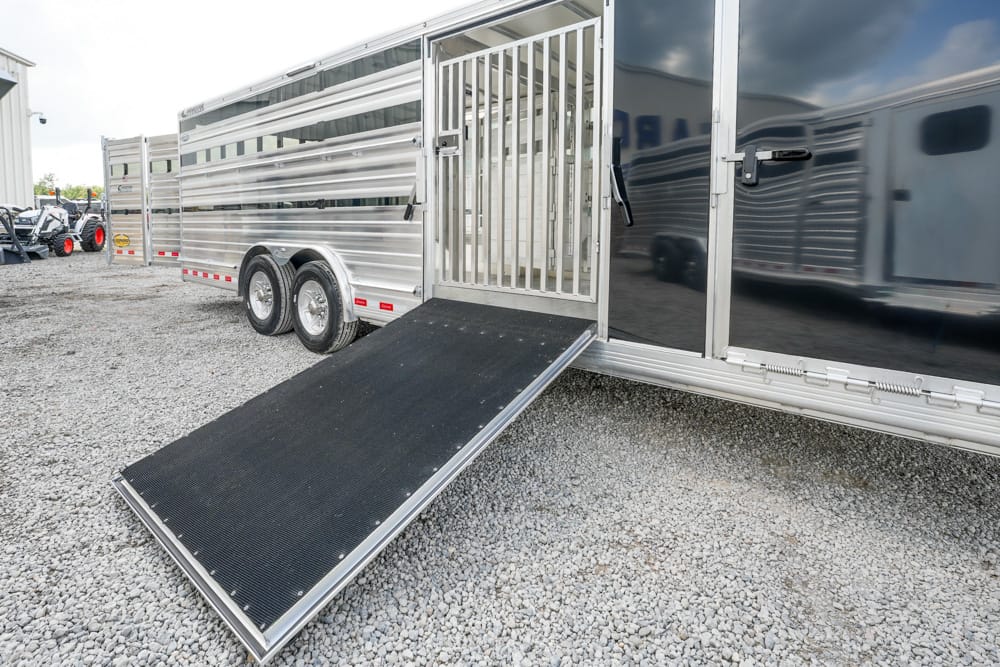 Silver horse trailer on a gravel lot with the ramp lowered for loading animals.