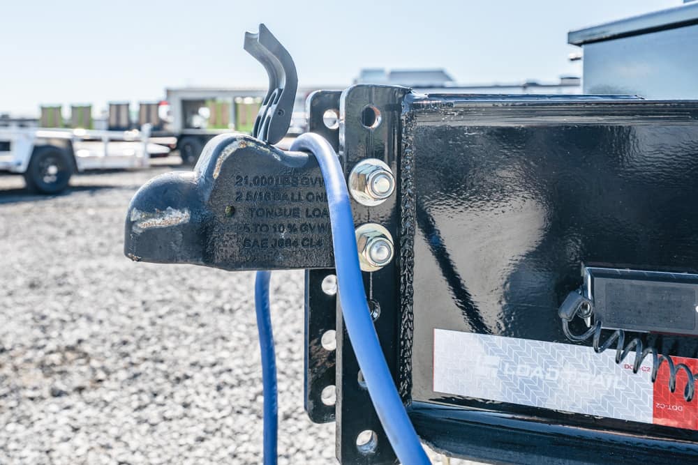 Close-up of a trailer hitch latch with a blue safety cable attached to a black trailer.