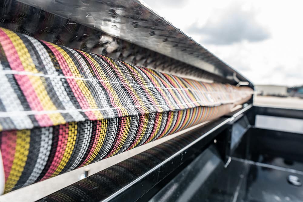Close-up of a colorful striped braided hose resting on a metal frame inside a truck bed.