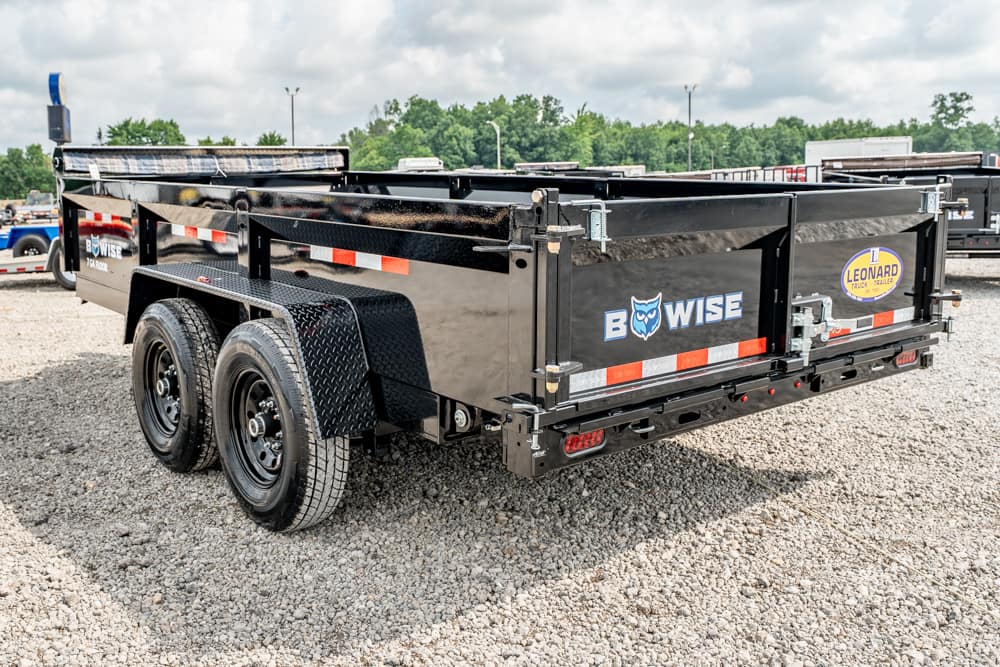 Black dual-axle dump trailer on a gravel lot, branded with BowWise and a Leonard sticker, with reflective tape along the sides.
