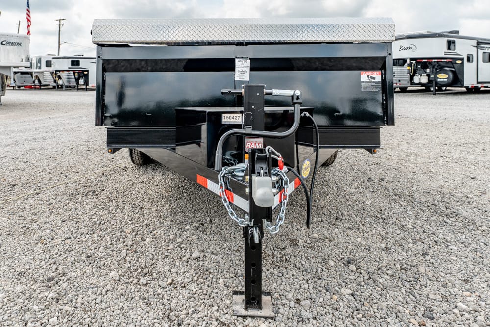 Front view of a black utility trailer on gravel, showing hitch, safety chains, and jack.