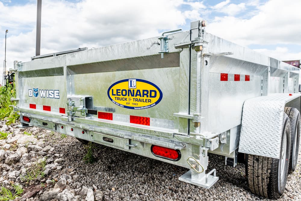 Heavy-duty galvanized trailer on a rocky surface, displaying Leonard Truck & Trailer logo.