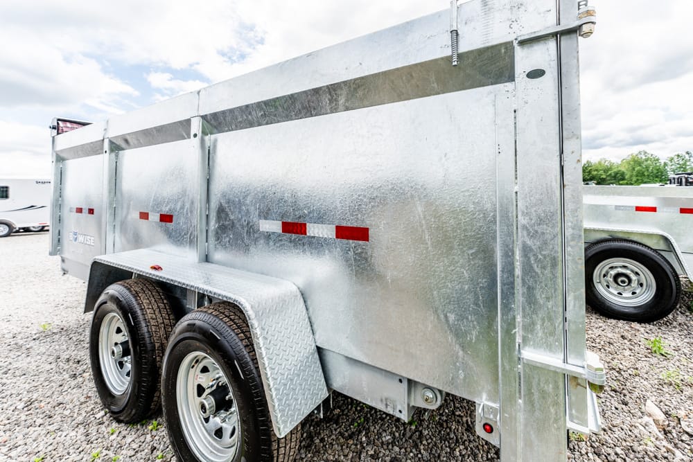 Shiny aluminum two-axle utility trailer on a gravel lot, shown from the side