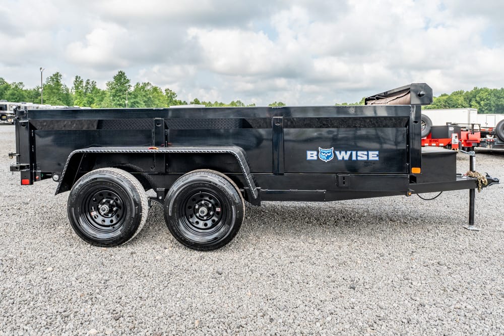 Black Bow-Wise dump trailer with dual axles and a raised tailgate on a gravel lot, branding visible on the side.