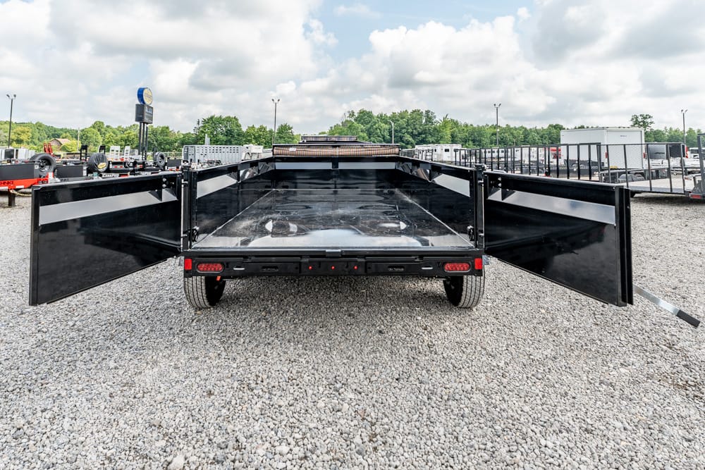 Black flatbed trailer viewed from the rear with its double doors wide open on a gravel lot.