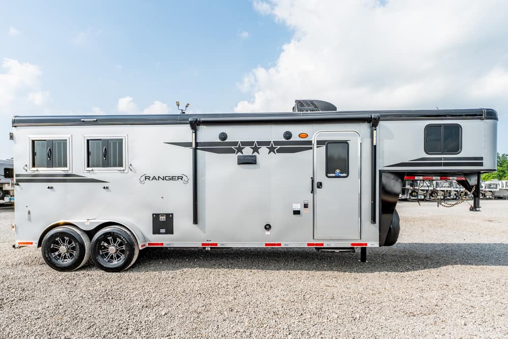 Silver Ranger horse trailer with two axles parked on a gravel lot, side view showing windows and doors.
