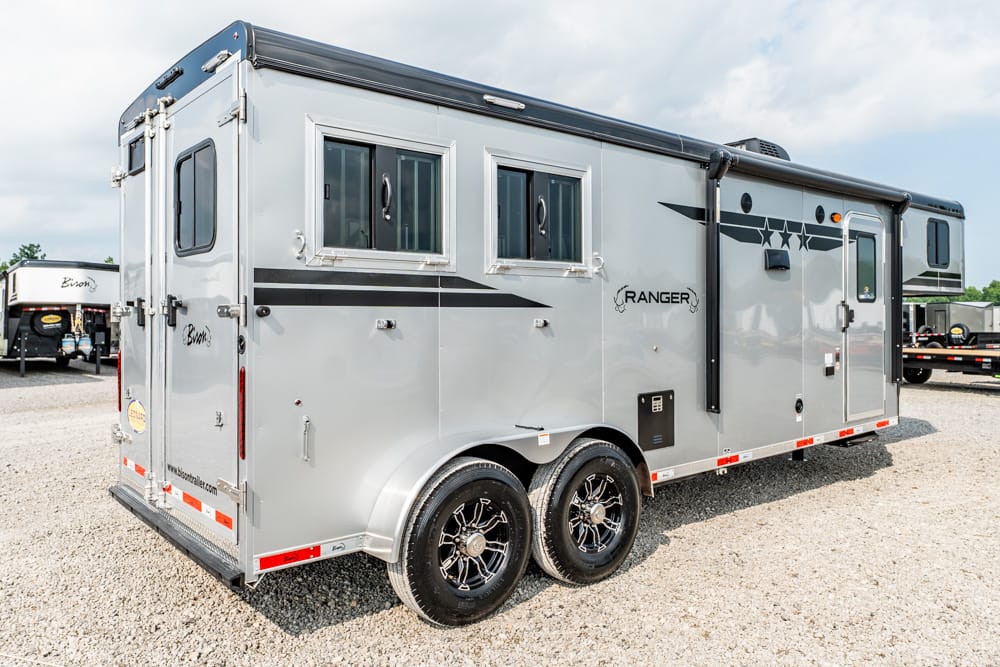 Gray Ranger horse trailer with dual axles and black side decals parked on gravel