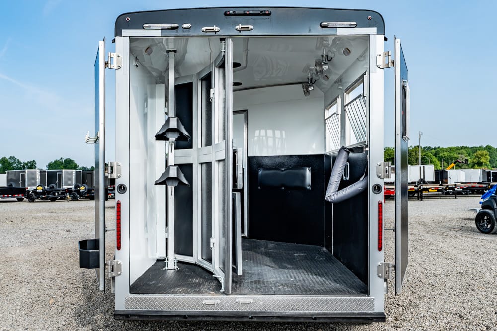 Open rear of a silver utility trailer with white interior, metal partitions, and a diamond-plate floor.