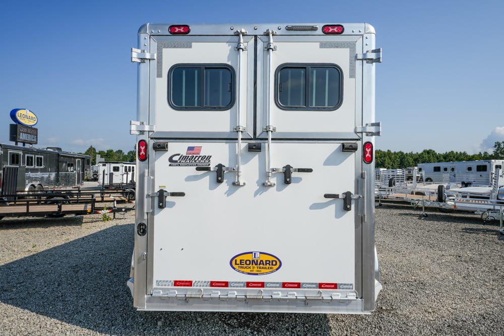 White cargo trailer back doors with latches and small windows, Leonard Trailer dealership lot in background
