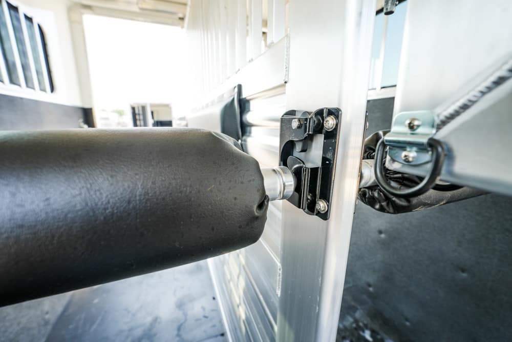 Close-up of a trailer door hinge and locking plate with a black padded roller in the foreground.