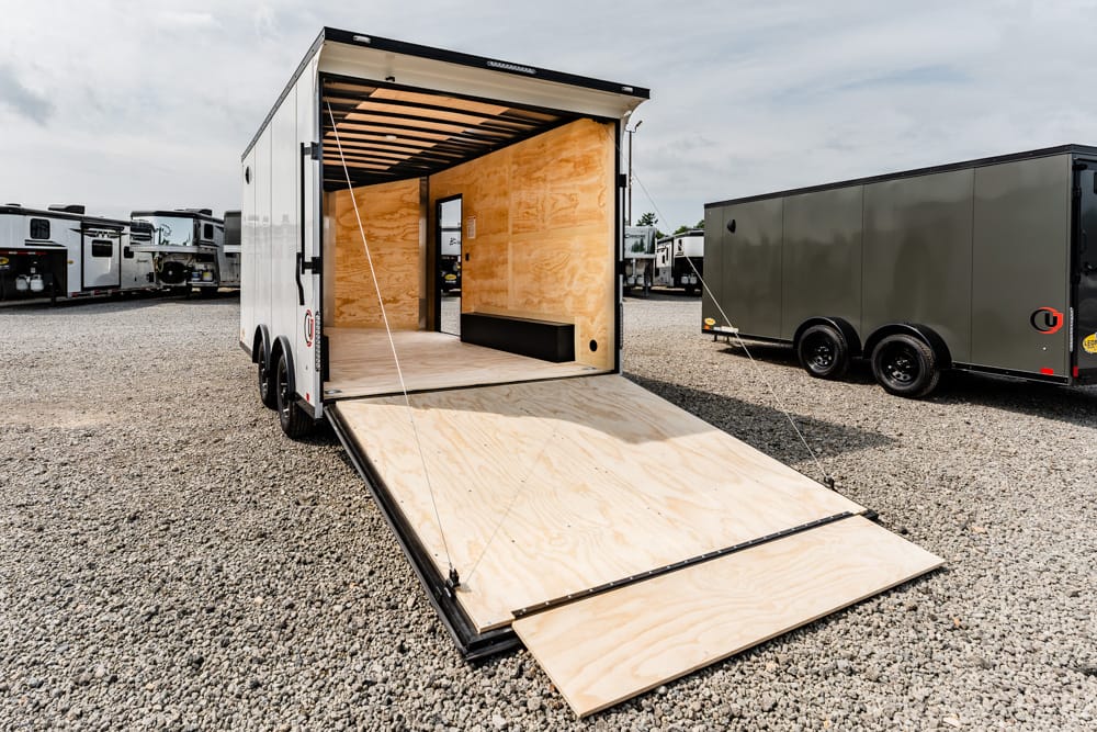 Open rear ramp trailer with plywood interior ready for loading cargo.