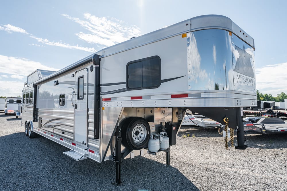 Fifth-wheel travel trailer with extended hitch and stabilizing legs parked on a gravel lot, propane tanks visible under the front, Merhow Summit logo on rear side.