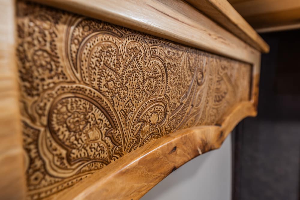 Close-up of an intricately carved wooden drawer front with floral paisley patterns on oak furniture.