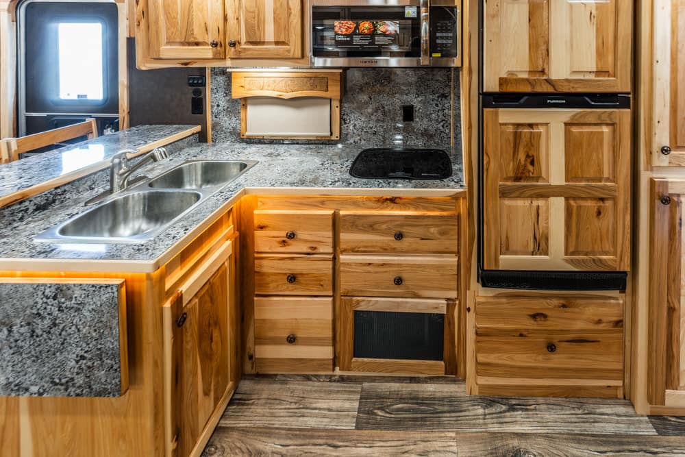 Rustic wooden kitchen with granite countertops, a double sink, and a built-in microwave above the counter.