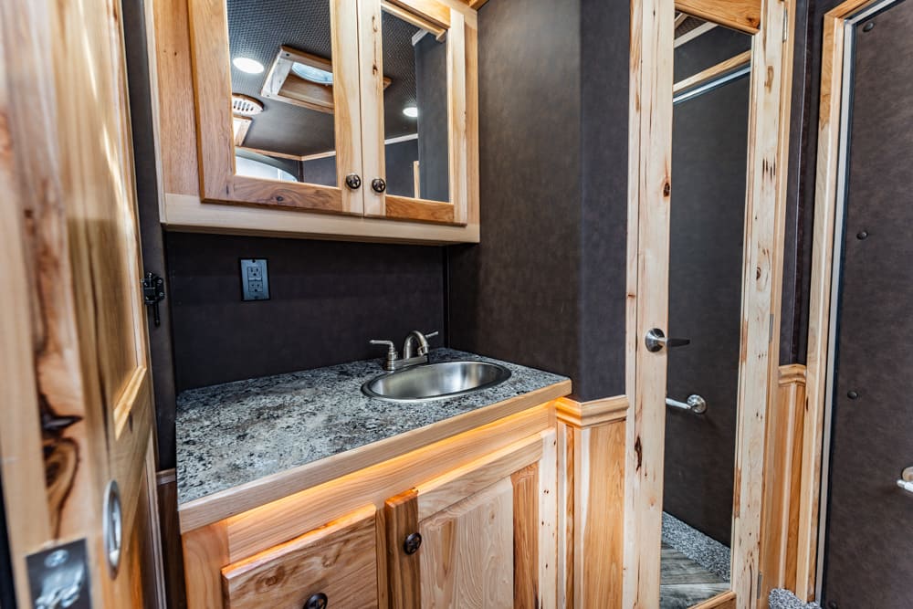 Rustic bathroom vanity with granite countertop, stainless steel sink, and mirrored cabinet above rooms.