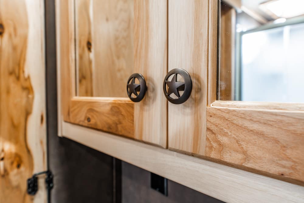 Close-up of rustic wooden cabinet doors with black star-shaped drawer pulls, highlighting the wood grain and natural finish.