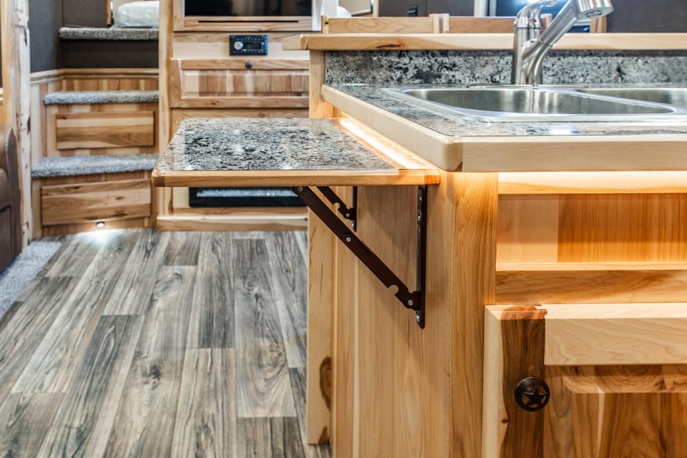 Wooden kitchen island with a granite fold-out counter extension and a stainless steel sink nearby