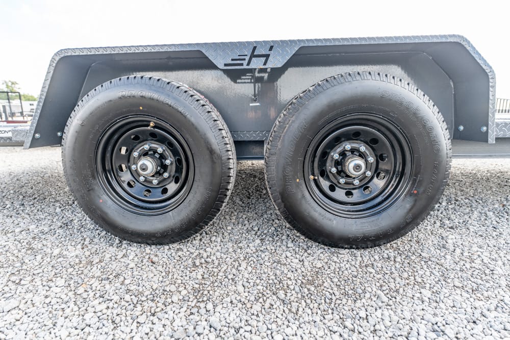 Dual-axle trailer with black steel wheels parked on gravel