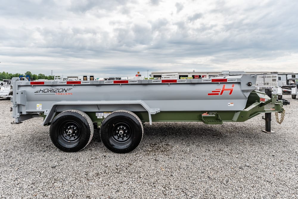 Grey Horizon dump trailer with dual axles parked on a gravel lot, showing the open-topped bed and red branding on the side.